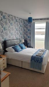 a bedroom with a bed with blue and white sheets and a window at HOTEL242 in Blackpool