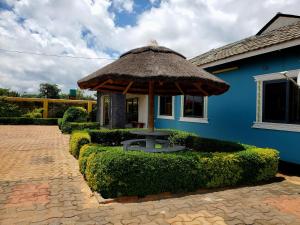 una casa azul con una sombrilla grande delante de ella en Sweet Retreat-1, en Lusaka