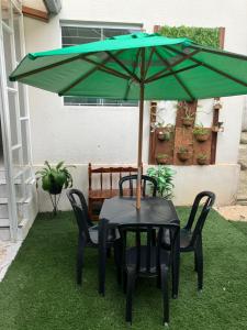 uma mesa e cadeiras com um guarda-sol verde em Duplex do Largo em Curitiba