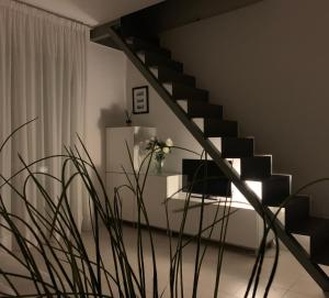 un escalier dans un salon avec une plante dans l'établissement Poetto Apartment, à Quartu SantʼElena
