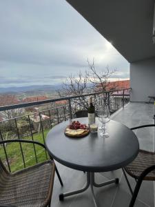 a table with a bottle of wine and glasses on a balcony at Apartment Ana in Imotski