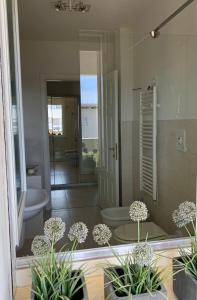 La salle de bains est pourvue d'une douche, de toilettes et de plantes. dans l'établissement Poetto Apartment, à Quartu SantʼElena