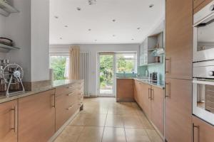 a large kitchen with wooden cabinets and a large window at Stunning three bedroom house with patio and garden in Preston