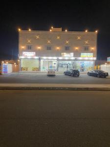 tres autos estacionados frente a un edificio por la noche en Etlalet Al-Sharm Apartments, en Yanbu