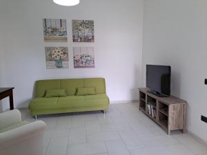 a living room with a green couch and a tv at I Sogni di Alice in Pula
