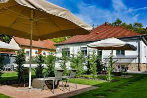 a patio with chairs and umbrellas in front of a house at Villa Garden in Eger