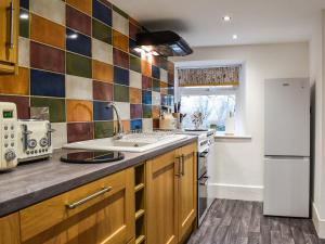 a kitchen with a sink and a refrigerator at Stork Cottage in Conder Green