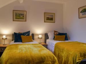 a bedroom with two beds with yellow sheets and lamps at Stork Cottage in Conder Green