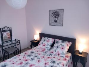 1 dormitorio con 1 cama con colcha de flores y 2 lámparas en Jolie F2 à 5mn de l'aéroport d'Orly, en Paray-Vieille-Poste