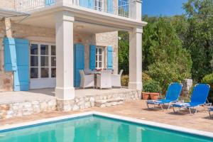 a house with a swimming pool and blue chairs at Villa Pelagos in Tselendáta