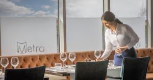 a woman standing in front of a table with wine glasses at Metro Apartments Dublin Airport in Dublin