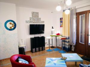 ein Wohnzimmer mit einem TV und einem roten Stuhl in der Unterkunft Marina Esuri Golf y Playa in Ayamonte