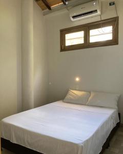 Cama blanca en habitación con ventana en Habitación privada en la playa HappyBeach_co, en San Antero