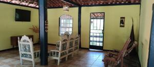 a room with chairs and a tv and two windows at Pousada Beira Rio Cipó in Serra do Cipo