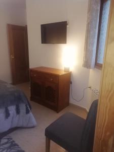 Schlafzimmer mit einem Bett, einem TV und einem Stuhl in der Unterkunft Cruz de Vino in Caravaca de la Cruz