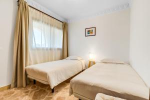 two beds in a room with a window at Hotel Castillo de Monda in Monda