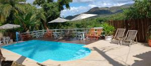 uma piscina com cadeiras, uma mesa e um guarda-sol em Pousada Beira Rio Cipó em Serra do Cipo