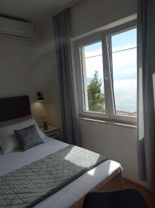 ein Schlafzimmer mit einem Bett und einem großen Fenster in der Unterkunft Apartments Mirko in Mimice