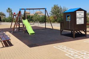 un parque infantil con un tobogán verde y una estructura de juegos en EL REMANSO IV, en La Manga del Mar Menor