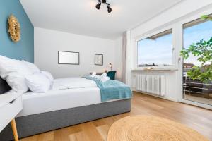 a white bedroom with a bed and a window at E&K living - design apartment - 2 bedrooms - kitchen - free parking in Augsburg