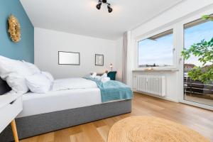 a white bedroom with a bed and a window at E&K living - design apartment - SKY-TV - kitchen - free parking in Augsburg
