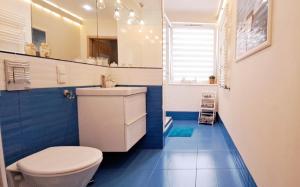 ein Badezimmer mit einem weißen WC und blauen Fliesen in der Unterkunft Marine Apartament in Danzig