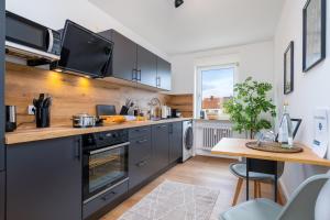 cocina con electrodomésticos de acero inoxidable y mesa de madera en E&K living - design apartment - 2 bedrooms - kitchen - free parking, en Augsburg