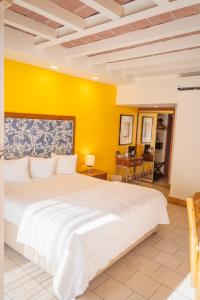 a bedroom with a white bed and a yellow wall at Hotel Posada El Rey Sol in Ensenada
