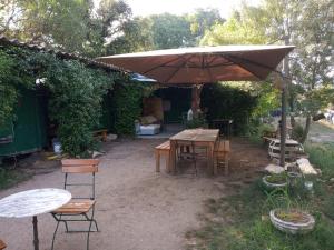 a patio with an umbrella and tables and chairs at Hébergement insolite nature/4 in Saint-André-de-Sangonis