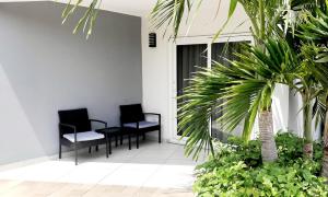 Arena Condominium Aruba في شاطئ بالم إيغل: كرسيين وطاولة في غرفة بها نباتات