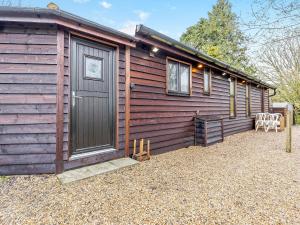 a wooden cabin with a door and a table and chairs at Piglets House - Uk43488 in Aldington