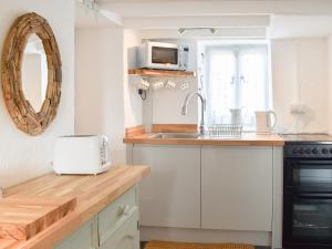 a kitchen with a sink and a microwave at The Yard Beach Cottage - Uk43653 in Clynnog-fawr