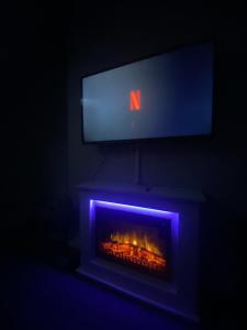 a tv above a fireplace with a fire in it at Cosy 2 Bedroom Flat in Sunderland in Sunderland