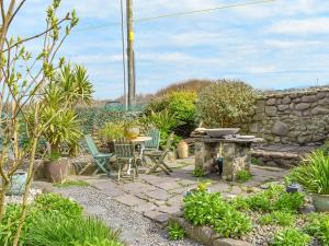 a patio with a table and chairs and a stone wall at The Yard Beach Cottage - Uk43653 in Clynnog-fawr