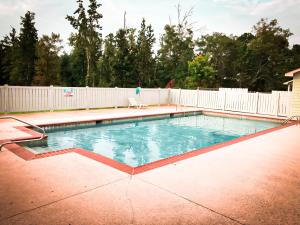 a swimming pool in a backyard with a white fence at Weiss Lake Lodge in Centre