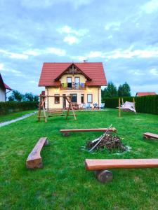 ein Haus mit einem Hof mit Baumstämmen im Gras in der Unterkunft Jeziorowskie Wspomnienia in Jeziorowskie