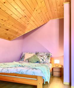 Schlafzimmer mit lila Wänden und Holzdecke in der Unterkunft Jeziorowskie Wspomnienia in Jeziorowskie