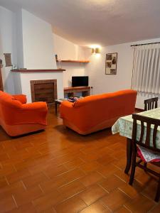 2 sofás naranjas en una sala de estar con chimenea en Casa vacanze Antolia en Abatemarco