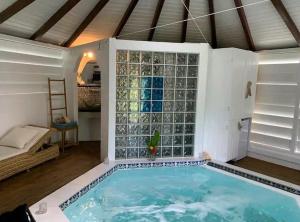 a swimming pool in a room with a large glass wall at Le grand palm gîte tobago in Les Basses