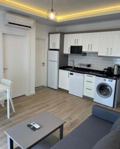 a kitchen and living room with white cabinets and a table at KALİDA APART in Kemer