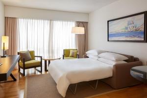 a hotel room with a bed and a desk and chairs at Sheraton Rhodes Resort in Ixia
