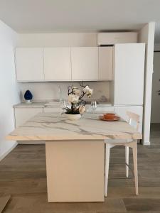 a kitchen with white cabinets and a table with flowers on it at BOUTIQUE HOME LIGNANO in Lignano Sabbiadoro