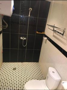 a bathroom with a toilet and a black tiled wall at Résidence le HAMEAU de BITENG in Yaoundé