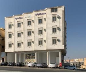 a large white building with cars parked in front of it at هدوء الليالي للأجنحة الفندقية in Khamis Mushayt