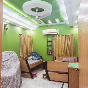 een kamer met 2 bedden en een groene muur bij White Lotus Corporate Business Boutique in Karachi