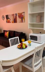 a white table with a plate of fruit and a microwave at Olivia SunSet Uno in Puerto de Santiago