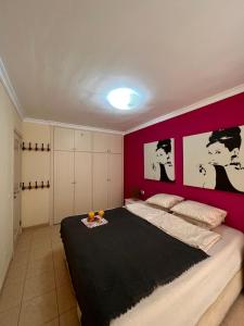 a bedroom with a large bed with a red wall at Olivia SunSet Uno in Puerto de Santiago +23 photos