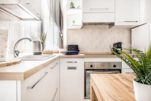 uma cozinha com armários brancos e um vaso de plantas em [Pretty House Navigli-Duomo] Netflix & Design em Milão