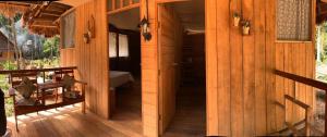 Casa de madera con porche y dormitorio en PAMPA HERMOSA LAKE RESORT, en Puerto Maldonado