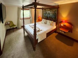 a bedroom with a four poster bed and a television at Dalgarven Spa House in Dalry